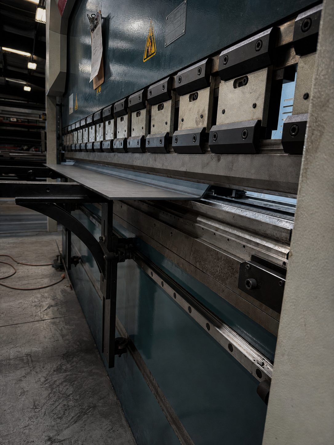 Close-up of press brake punch and die tooling with a steel sheet in position