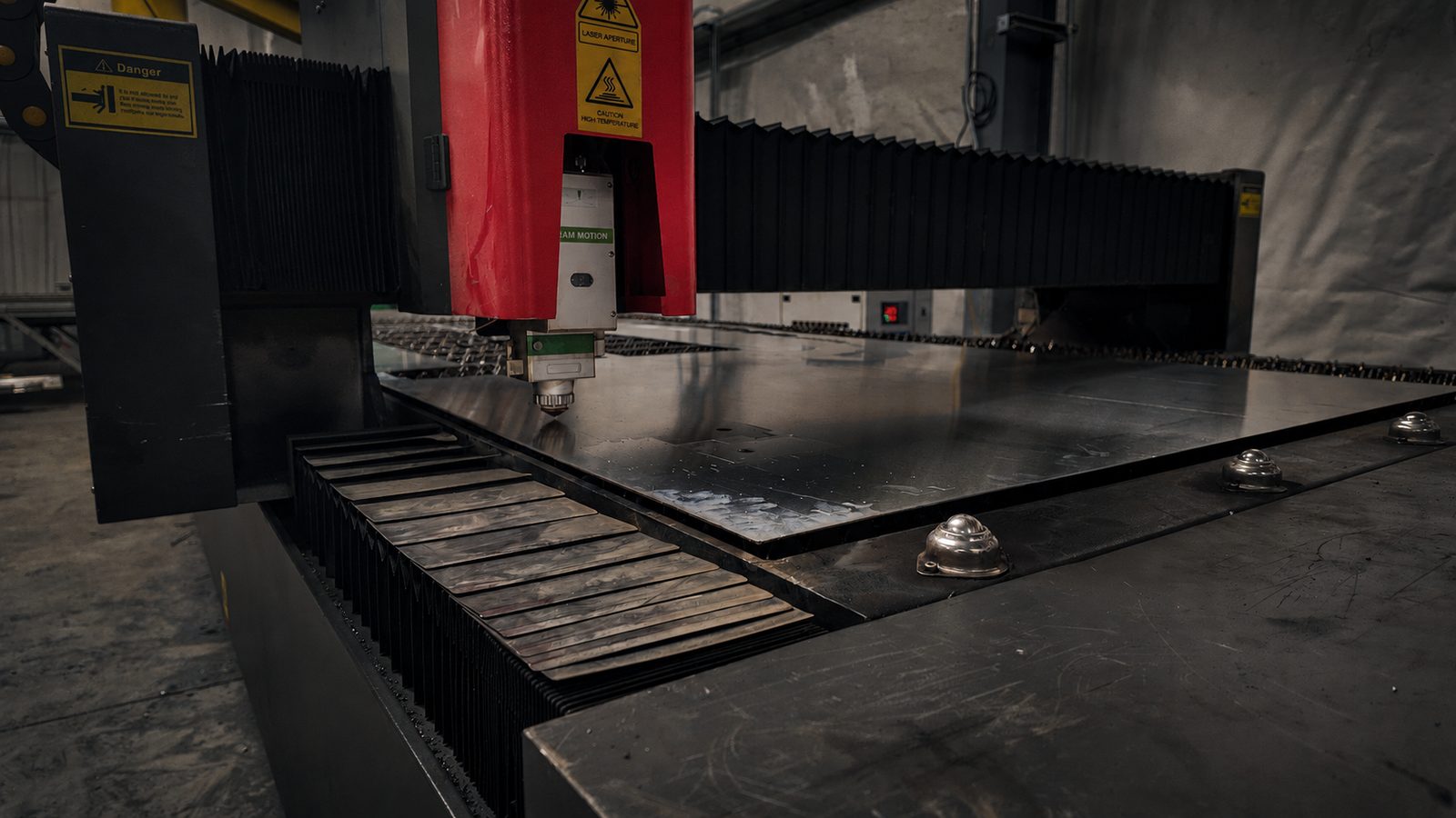 Laser cutting head positioned over sheet steel on the slat bed