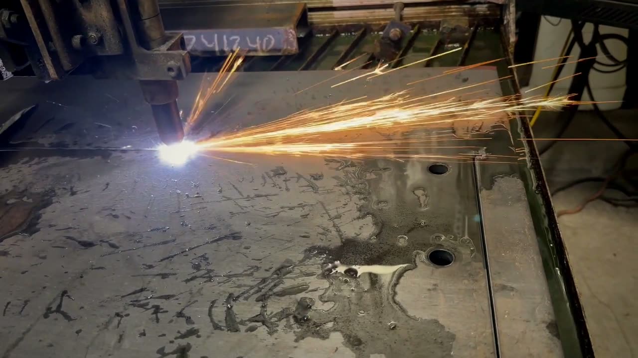 Laser cutting head throwing sparks as it cuts steel plate