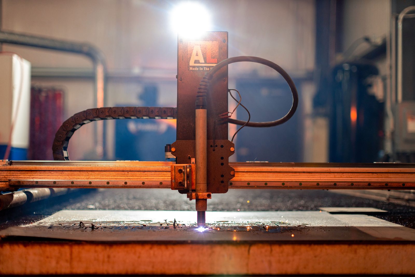 Laser cutting head lit over sheet steel on the machine bed