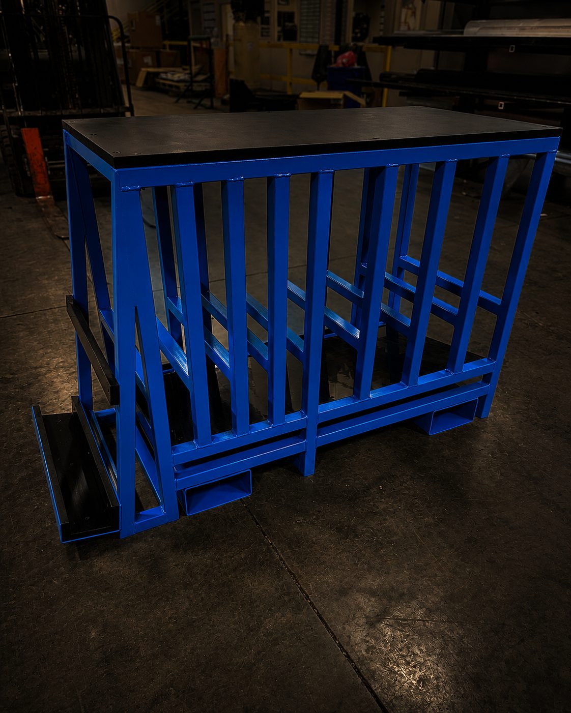 Blue steel bench frame with a dark top standing on a shop floor