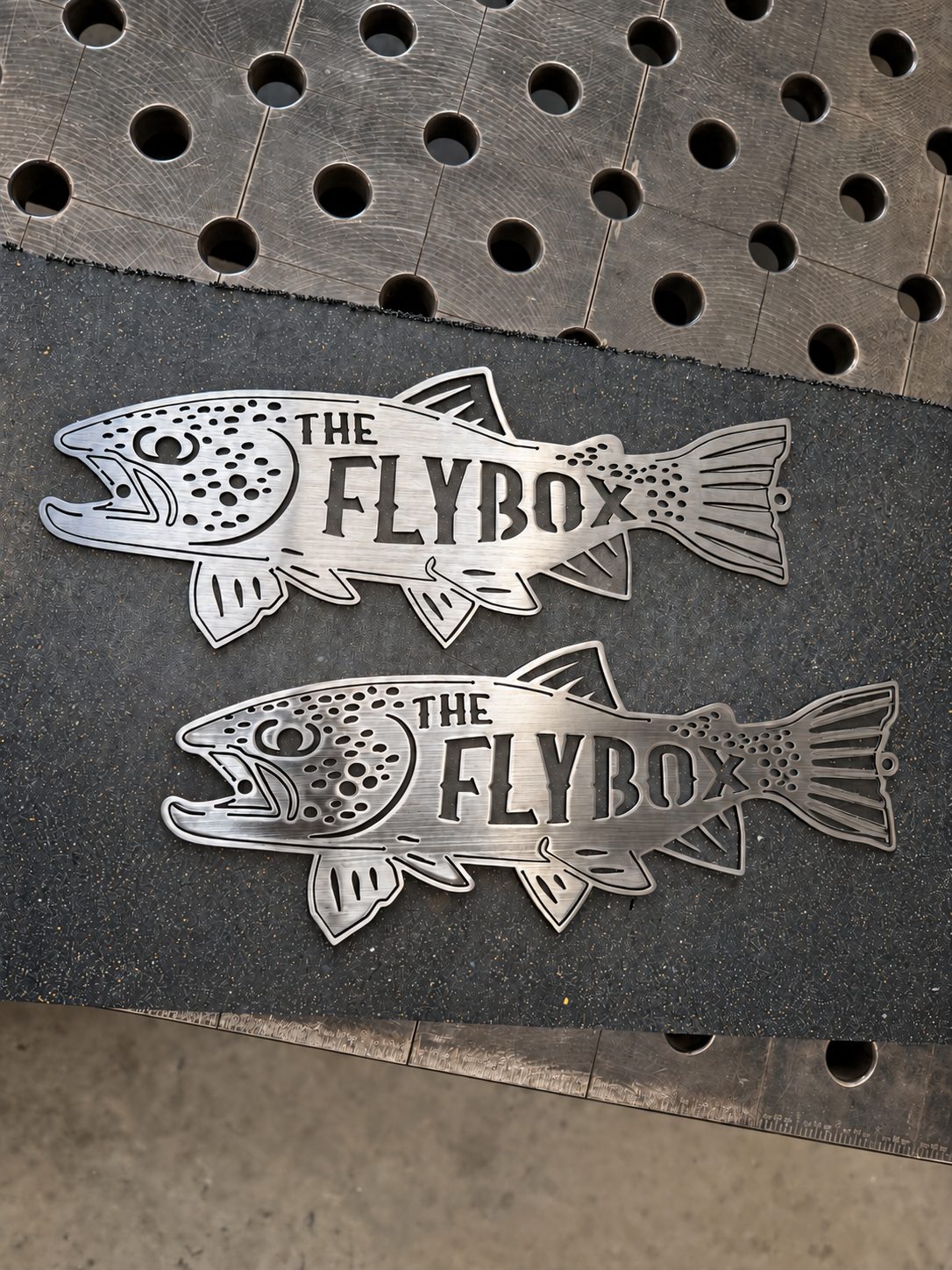 Two custom laser-cut steel fish signs reading The Flybox